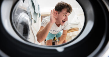 Man view from washing machine inside. Male does laundry daily ro