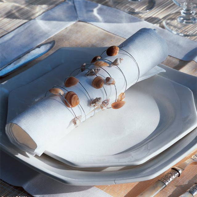 Белая салфетка с ракушками на тарелке